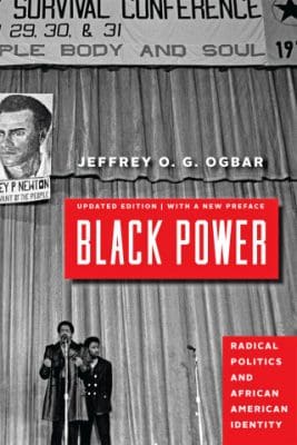 The image is a book cover for "Black Power: Radical Politics and African American Identity" by Jeffrey O. G. Ogbar, updated edition. The cover features a black and white photo of two individuals in suits standing in front of a microphone with the title text overlaid in bold red letters. Behind them is a sign for a Survival Conference dated August 29, 30, & 31 for 'People Body and Soul,' with a background of corrugated metal siding. The book author's name is printed at the top, and additional text at the bottom of the cover proclaims the updated edition with a new preface.