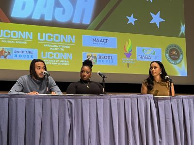 Three panel speakers seated behind a table on stage