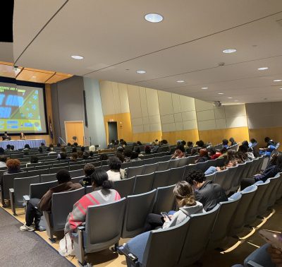 Image of the Student Union Theater with guests seated watching panel discussion