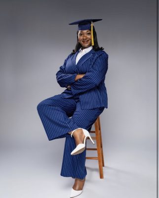 Trinity Stewart sitting on stool in graduation cap
