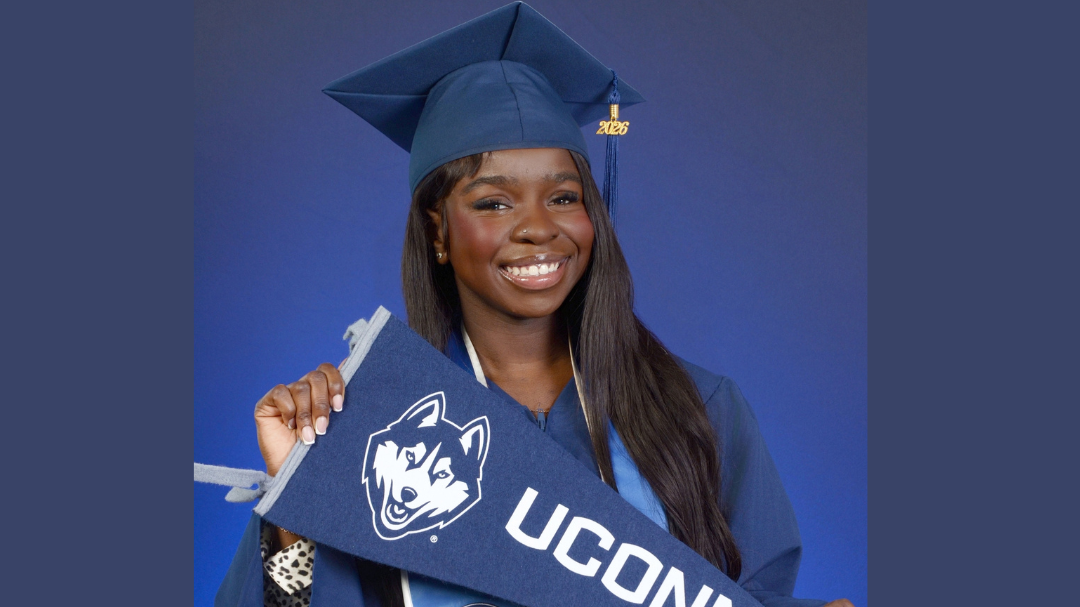 Anna Charles Graduation headshot holding UConn Banner